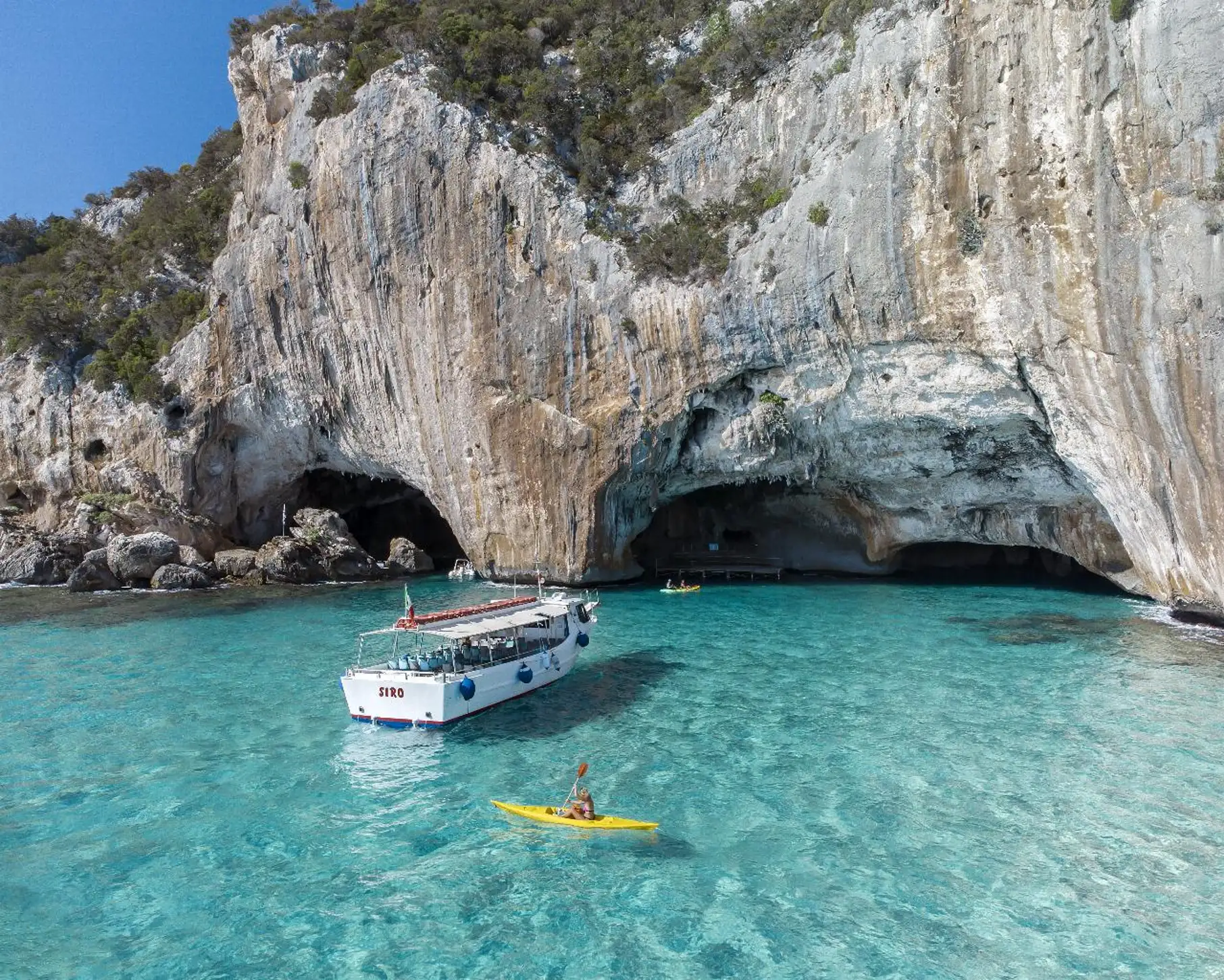 Boat and kayak at cave entrance in the Gulf of Orosei