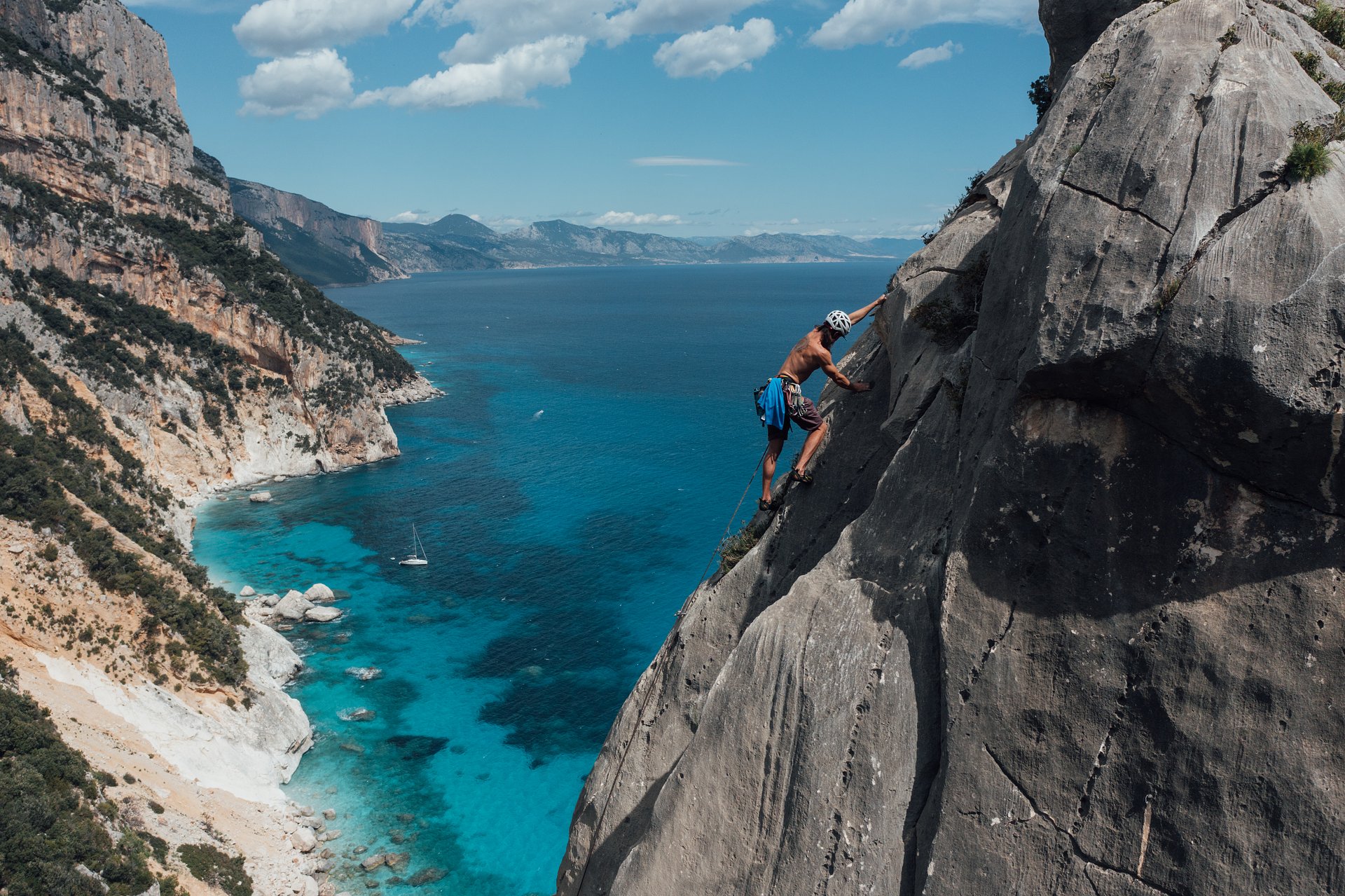 Rock climber on limestone cliff above the Gulf of Orosei