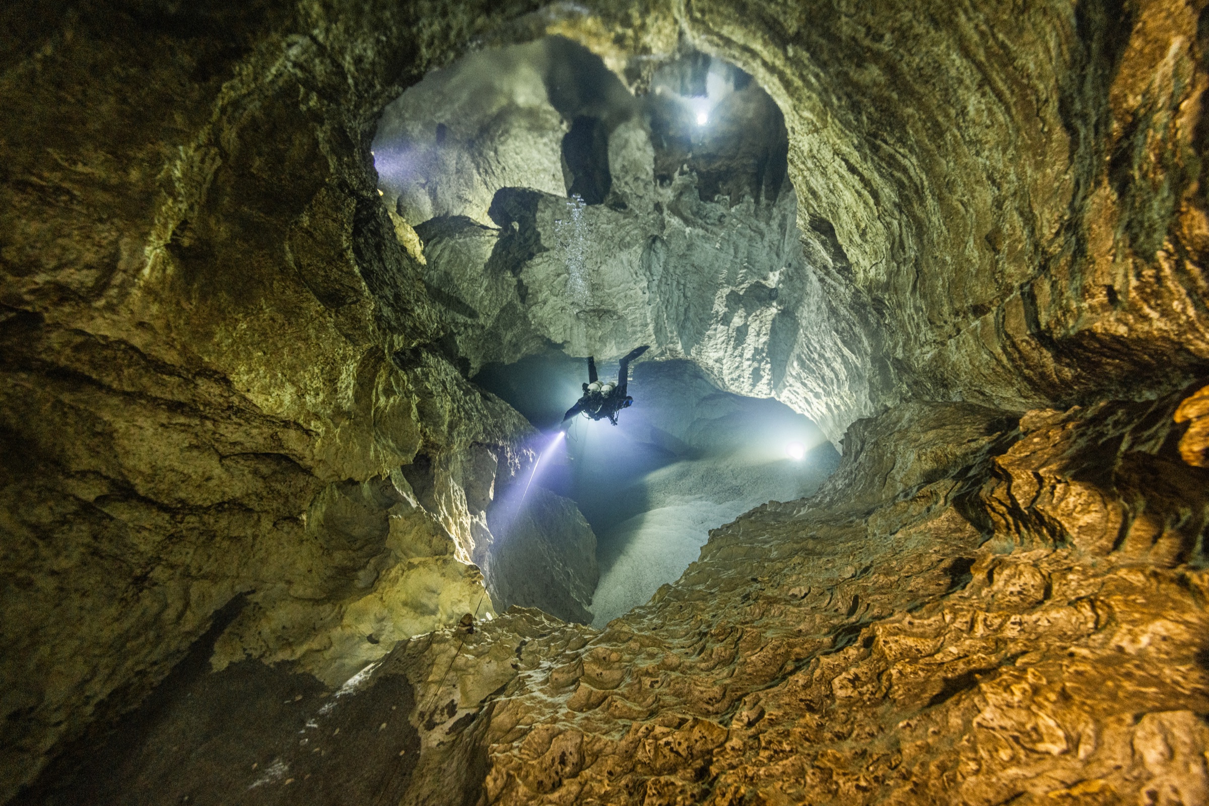 Diver looking up through dramatic cave ceiling