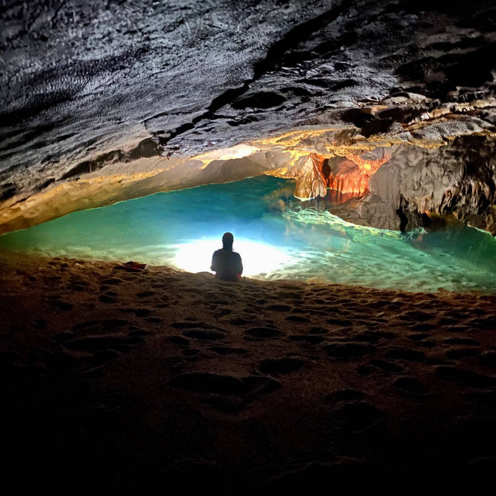 Diver silhouette in a glowing cave pool